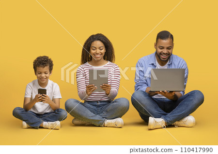 Family Gadgets. Black parents and little son using different electronic devices Family Gadgets. Black parents and little son using different electronic devices 110417990