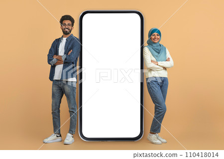 Mobile offer. Smiling muslim couple leaning on giant blank smartphone Mobile offer. Smiling muslim couple leaning on giant blank smartphone 110418014