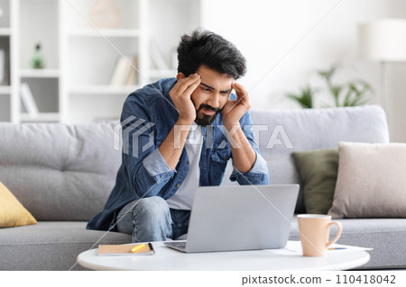 Stressed indian man having headache while working on laptop at home Stressed indian man having headache while working on laptop at home 110418042
