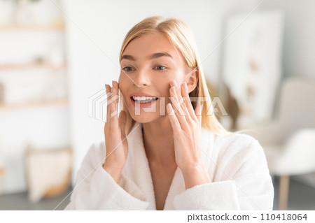 Joyful woman with blonde hair touching soft skin in bathroom 110418064