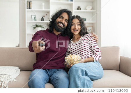 Positive millennial indian man and woman watching TV 110418093