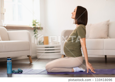 Young pregnant woman performs backbend exercise on fitness mat indoor 110418096