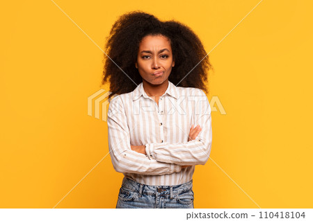 Skeptical black lady with arms crossed on yellow background Skeptical black lady with arms crossed on yellow background 110418104