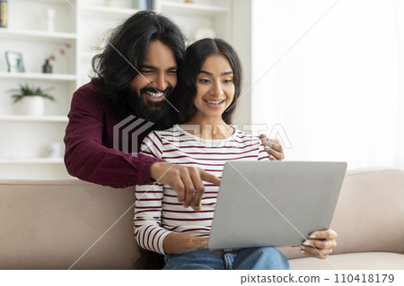Happy indian couple looking at laptop and choosing purchase Happy indian couple looking at laptop and choosing purchase 110418179