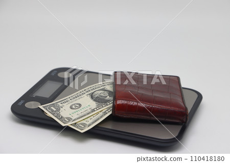 Brown wallet with banknotes on electronic kitchen scales. Symbol of accounting and family finance planning. Brown wallet with banknotes on electronic kitchen scales. Symbol of accounting and family finance planning. 110418180