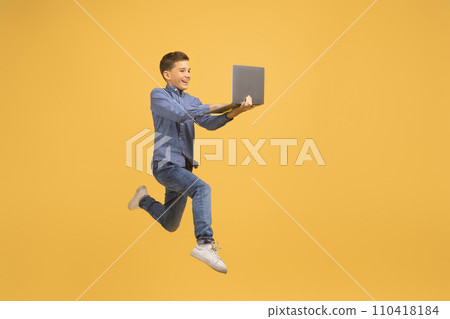 Excited Teen Boy With Laptop Computer In Hands Jumping On Yellow Background Excited Teen Boy With Laptop Computer In Hands Jumping On Yellow Background 110418184