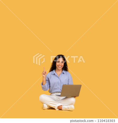 Engaged young woman with a laptop sits on a yellow background Engaged young woman with a laptop sits on a yellow background 110418303