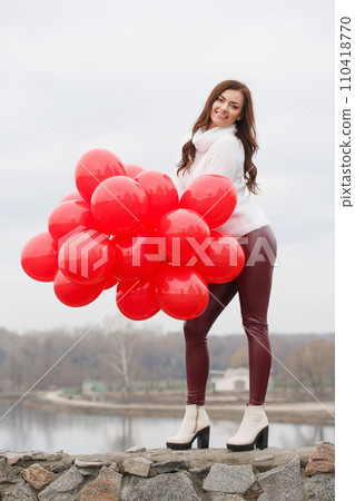 Young woman with red balloons, outdoors, full length photo. 110418770