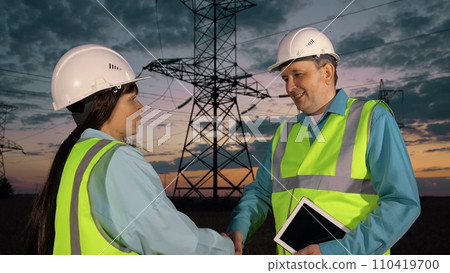 Technician with tablet and inspector shake hand at power distribution substation 110419700