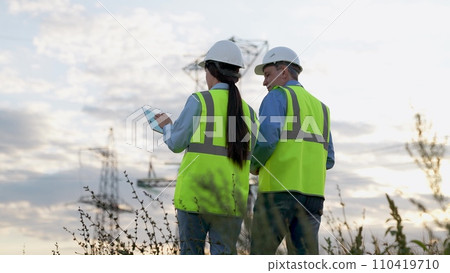 Engineer and safety inspector with tablet walk to power transmission lines Engineer and safety inspector with tablet walk to power transmission lines 110419710