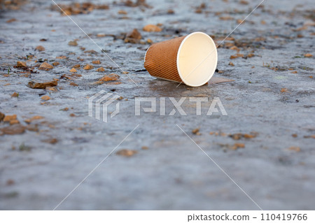 Empty paper coffee cup left on the ground, recyclable waste Empty paper coffee cup left on the ground, recyclable waste 110419766