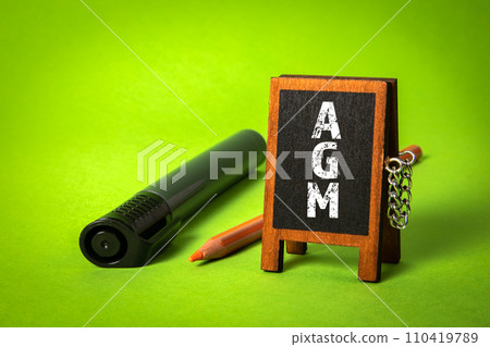 AGM Annual general meeting. Miniature chalkboard on a green background 110419789