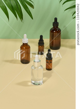 Glass bottles for cosmetics, oils with a pipette on a beige background Glass bottles for cosmetics, oils with a pipette on a beige background 110420042
