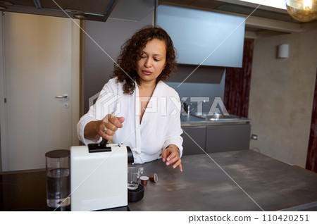 Beautiful curly haired brunette woman preparing espresso coffee for breakfast in the morning 110420251