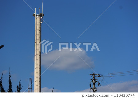 Cityscape with clouds, blue sky, green leaf trees, chimneys, telephone poles, and wires Cityscape with clouds, blue sky, green leaf trees, chimneys, telephone poles, and wires 110420774