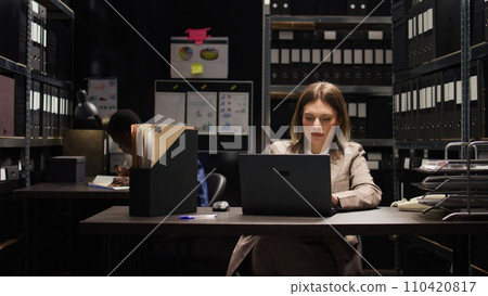 In crime investigation, focused male and female investigators analyzing confidential suspect information. Caucasian detective uses personal computer to cross-check critical evidence and statements. In crime investigation, focused male and female investigators analyzing confidential suspect information. Caucasian detective uses personal computer to cross-check critical evidence and statements. 110420817