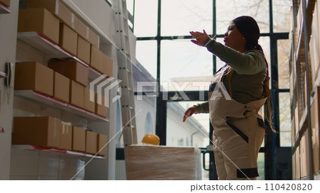 Manager in warehouse using AR holographic technology to visualize how to best stash parcels on shelves to make room for more. Supervisor in distribution center uses augmented reality Manager in warehouse using AR holographic technology to visualize how to best stash parcels on shelves to make room for more. Supervisor in distribution center uses augmented reality 110420820