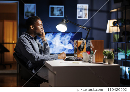 African american guy yawning while working at home and trying to solve problems before project deadline, financial study. Male freelancer feeling exhausted and overworked with new contract. 110420902