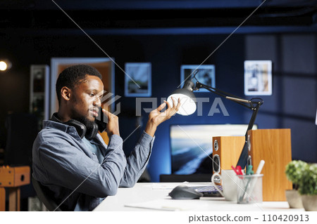 Male investor contacts his accountant at home desk to go over current budget balance, with objective to boost earnings via foreign investments. Man reviewing financial assets with consultant. Male investor contacts his accountant at home desk to go over current budget balance, with objective to boost earnings via foreign investments. Man reviewing financial assets with consultant. 110420913