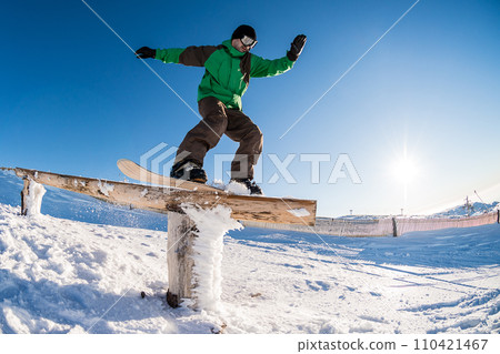 Snowboarder sliding on a rail Snowboarder sliding on a rail 110421467