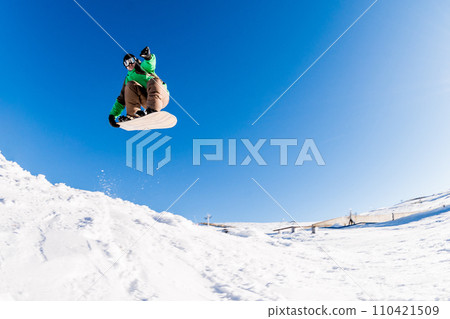Snowboarder jumping against blue sky Snowboarder jumping against blue sky 110421509