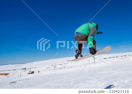 Snowboarder jumping against blue sky Snowboarder jumping against blue sky 110421518