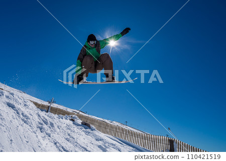 Snowboarder jumping against blue sky 110421519