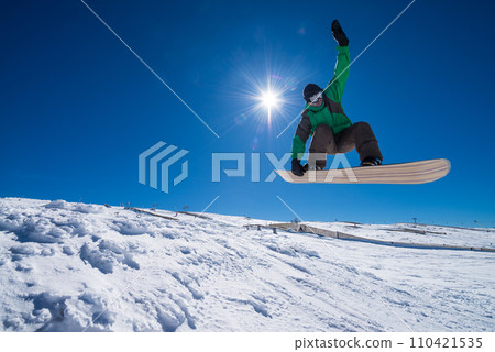 Snowboarder jumping against blue sky 110421535