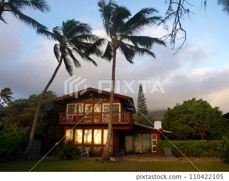 Sunrise reflects into the window of Red Beach House with tall coconut trees Sunrise reflects into the window of Red Beach House with tall coconut trees 110422105