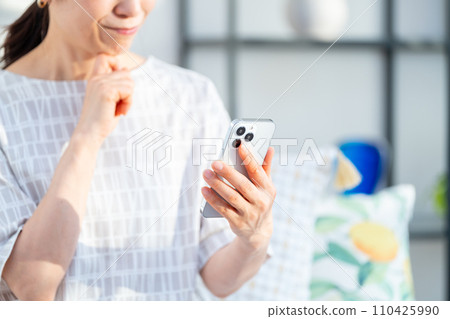一位操作智慧型手機的中年婦女。 （部分） 110425990