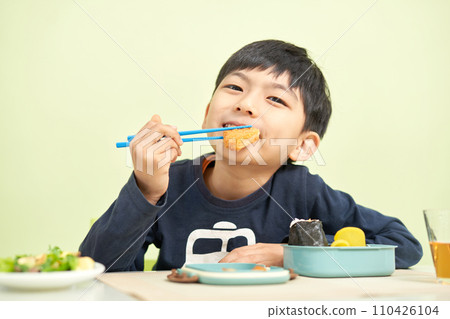 A young boy eating lunch with a smile 110426104
