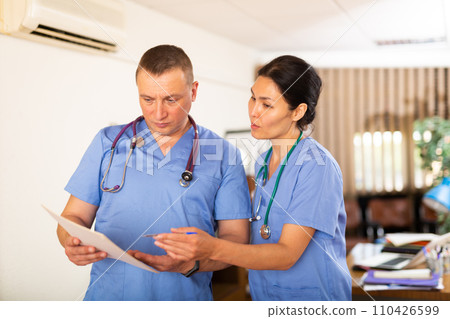 Two doctors checking patient papers in clinic Two doctors checking patient papers in clinic 110426599