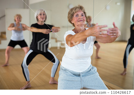 Mature women performing dance in exercise room Mature women performing dance in exercise room 110426617