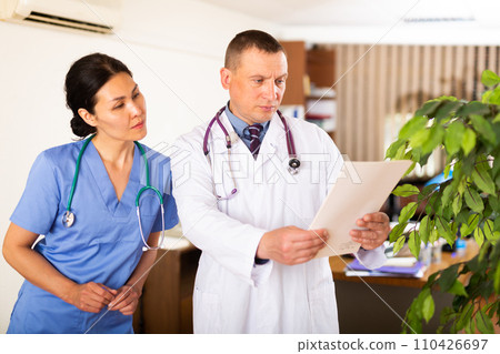 Two doctors checking patient papers in clinic Two doctors checking patient papers in clinic 110426697