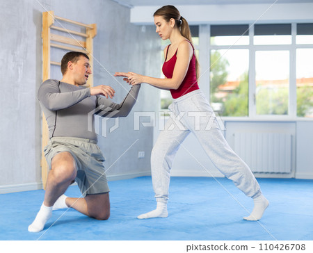 Young girl and middle-aged man practicing arm twist technique during self-defense courses 110426708