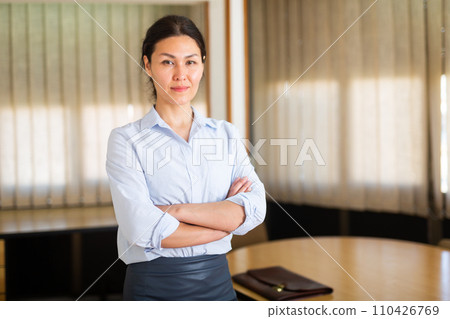 Successful business woman standing with arms crossed in office Successful business woman standing with arms crossed in office 110426769
