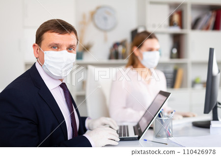 Entrepreneur in medical mask working with female coworker in office 110426978