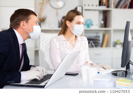 Businessman in face mask working with female assistant in office 110427053