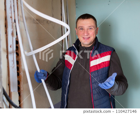 Repair man with cable duct standing in room and looking at camera 110427146
