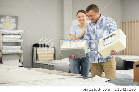 Family couple examining mattress cross-section samples in furniture store Family couple examining mattress cross-section samples in furniture store 110427150