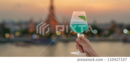 tourist hand shows cocktail glass during enjoy view to Wat Arun Temple in sunset, Traveler visits Temple of Dawn near from rooftop bar. Travel destination in Bangkok, Thailand and Southeast Asia tourist hand shows cocktail glass during enjoy view to Wat Arun Temple in sunset, Traveler visits Temple of Dawn near from rooftop bar. Travel destination in Bangkok, Thailand and Southeast Asia 110427187