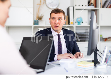 Businessman working in office with female colleague 110427205