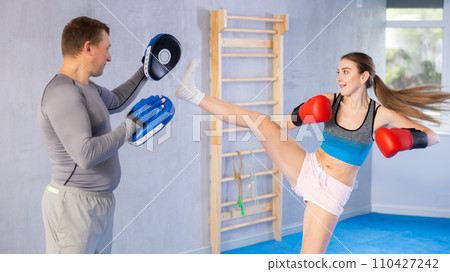 Adult man and young woman practicing boxing Adult man and young woman practicing boxing 110427242