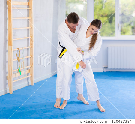 Young girl and middle-aged man wearing kimono training throwing technique Young girl and middle-aged man wearing kimono training throwing technique 110427384