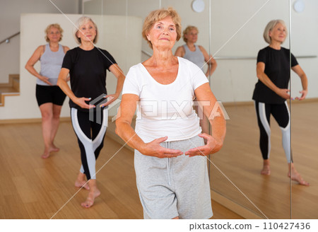 Senior women in sportswear dancing ballet inside gym 110427436