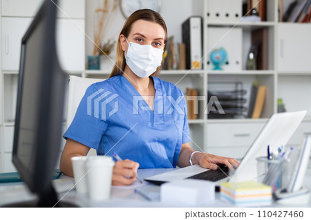 Female doctor in in protective medical mask working on laptop 110427460