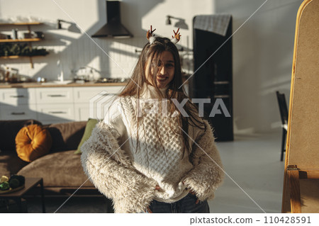 A sunny apartment setting: a lively young lady in a Christmas reindeer mask. 110428591