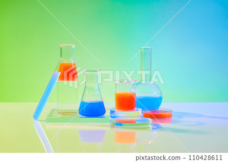 Laboratory glassware containing color liquid displayed on transparent podiums on green gradient background. Blank space for display product with minimal concept 110428611