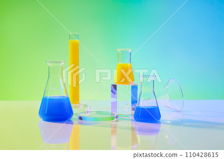 Laboratory equipment and science content with test tube and erlenmeyer flasks filled yellow and blue liquid on green gradient background. Lab background for display product. Front view Laboratory equipment and science content with test tube and erlenmeyer flasks filled yellow and blue liquid on green gradient background. Lab background for display product. Front view 110428615