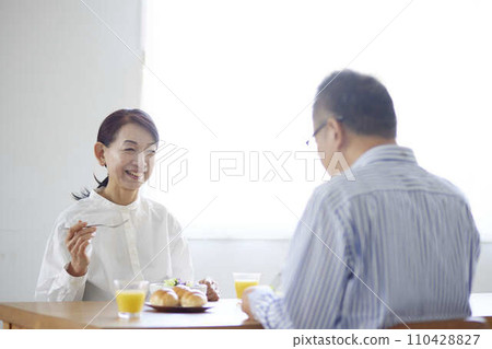 一對日本老年夫婦圍坐在餐桌旁吃早餐。 一對日本老年夫婦圍坐在餐桌旁吃早餐。 110428827